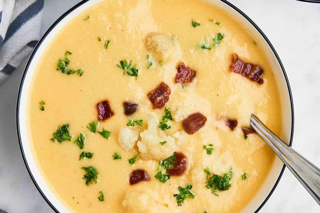 Cheesy cauliflower soup in a bowl with a spoon.