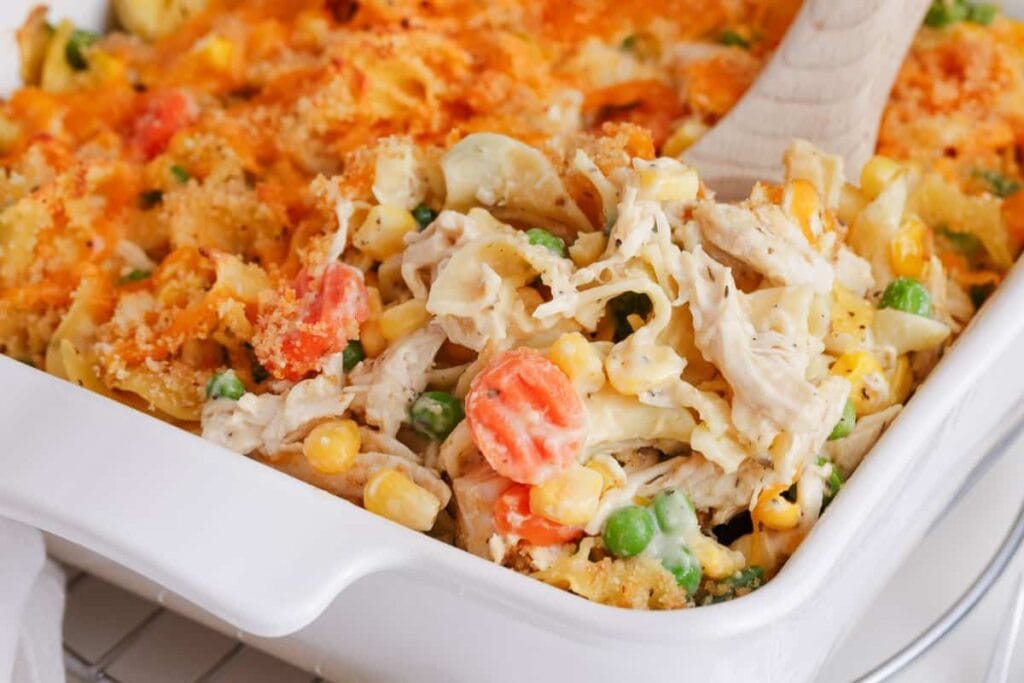 Chicken noodle casserole in a baking dish with a wooden spoon.
