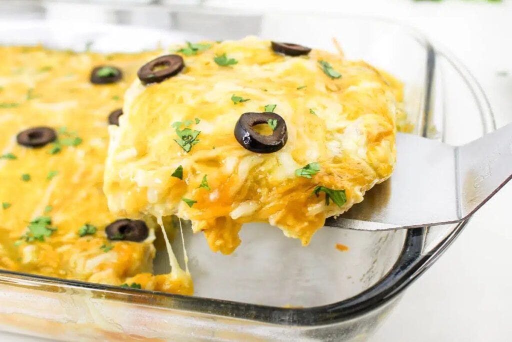 Cheesy chicken taquito casserole lifted with a spatula from a glass baking dish.
