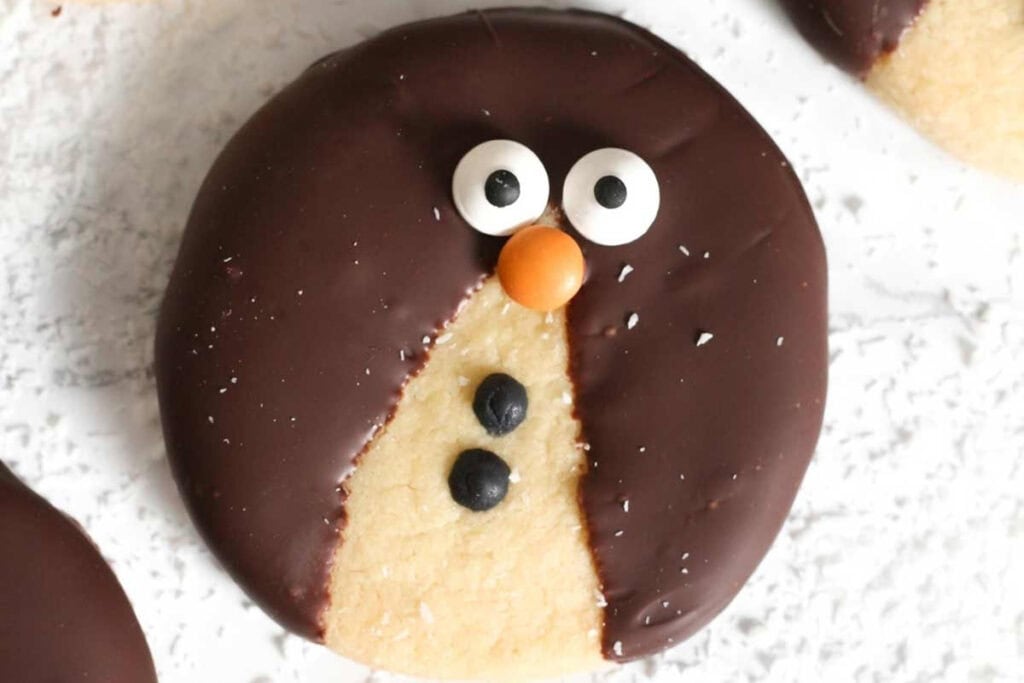 Penguin cookies with chocolate, candy eyes, and an orange nose.