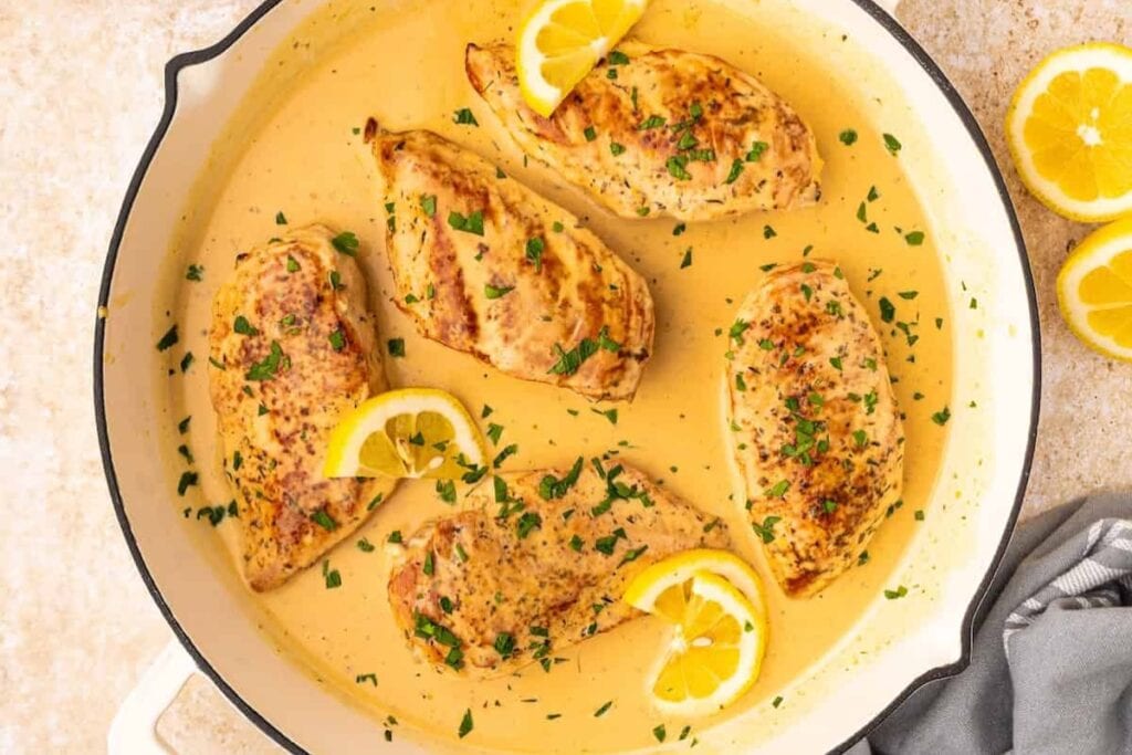 Creamy lemon chicken topped with herbs in a skillet.