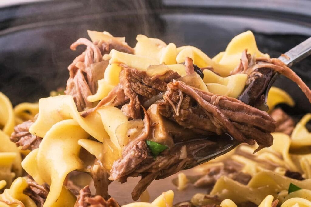 Close-up of crockpot beef and noodles on a fork.