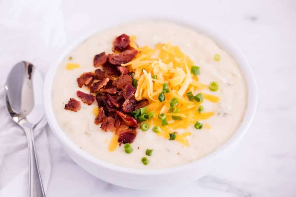 Crockpot potato soup in a bowl topped with bacon and cheese.