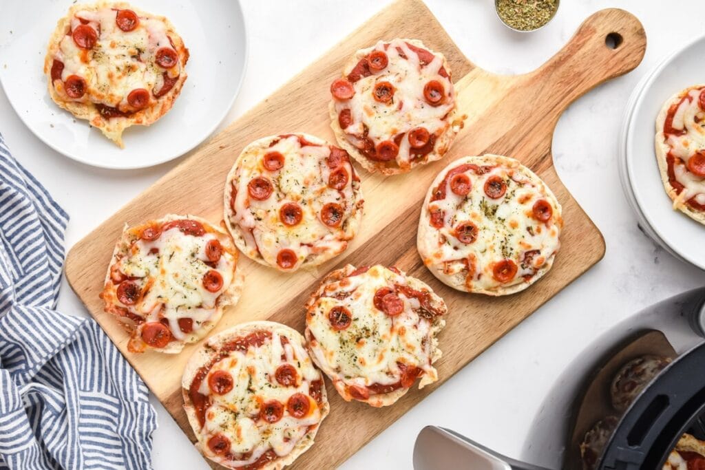 English muffin pizzas on a wooden board.