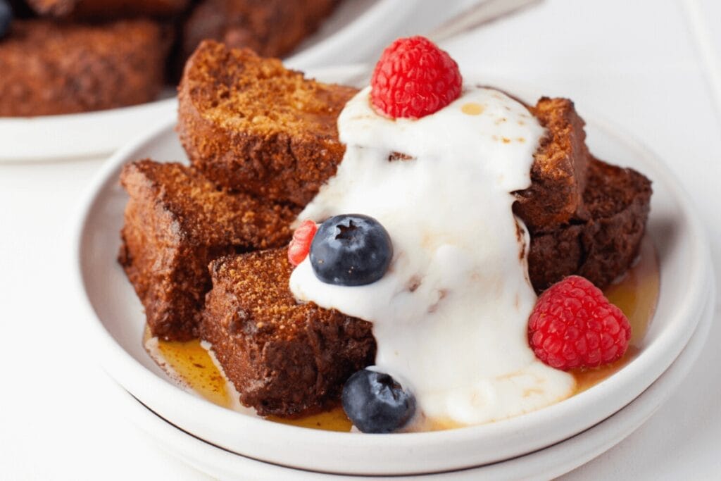 French toast sticks on a plate topped with berries.