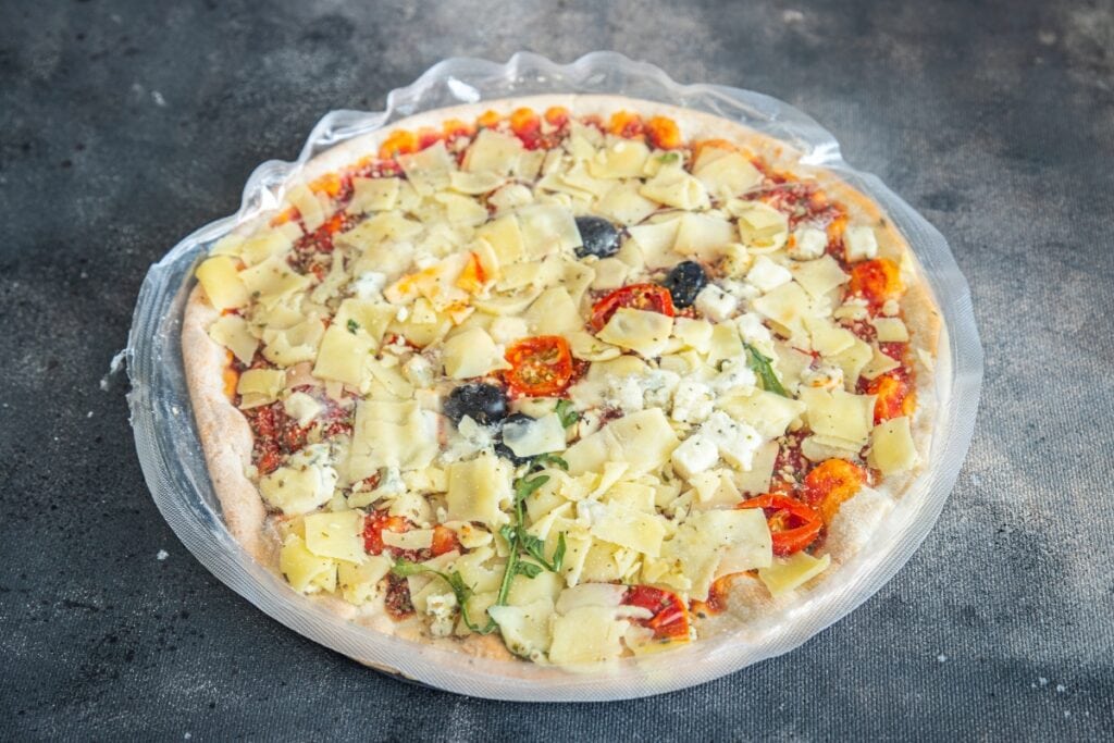 Packaged frozen pizza on gray surface.