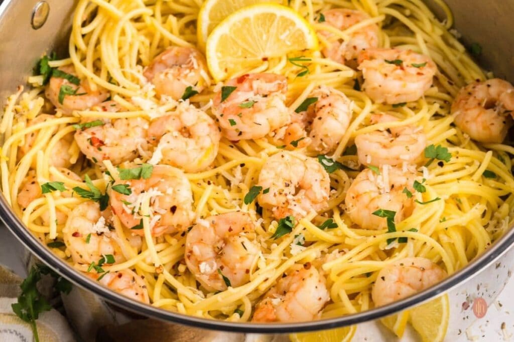 Garlic butter noodles with shrimp and lemon slices in a casserole dish.