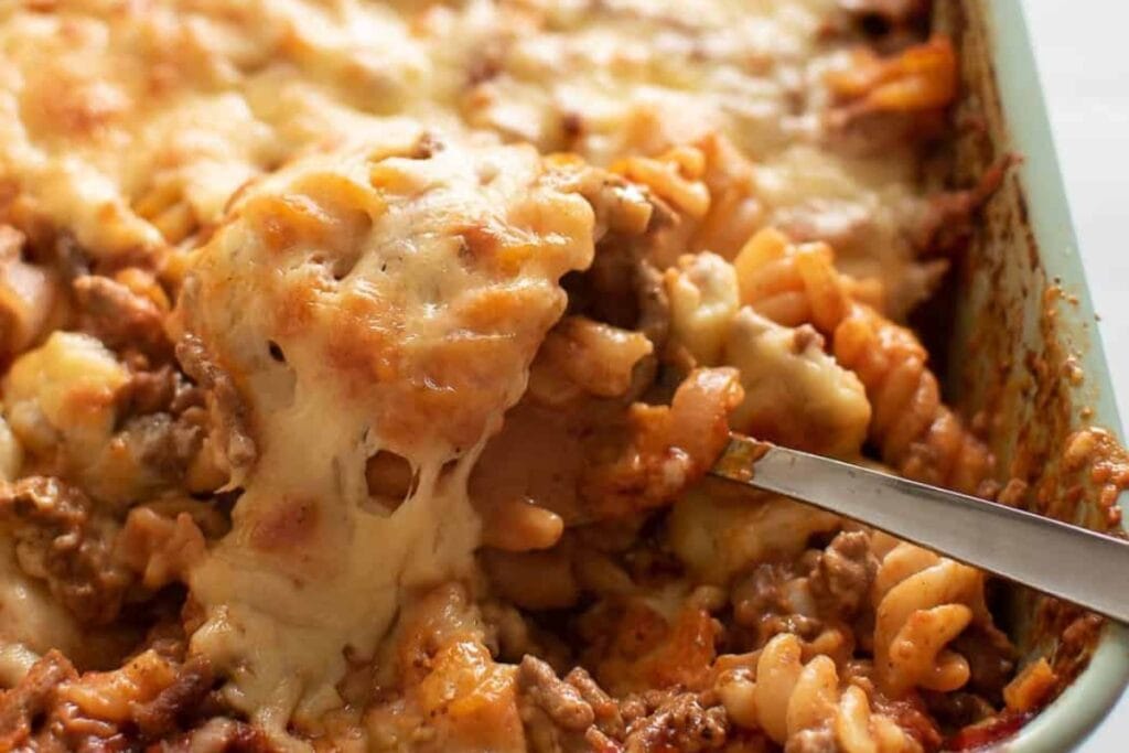 Spoon scooping hamburger casserole from a baking dish.