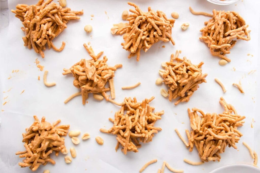 Haystack cookies made with chow mein noodles and chocolate on parchment paper.