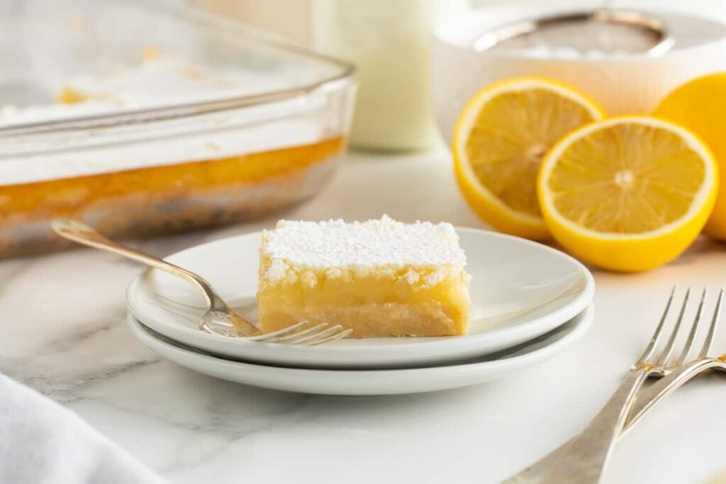 Lemon bar on a plate with a fork on the side.