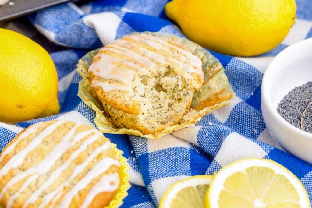 Lemon muffins with poppy seeds on blue fabric.