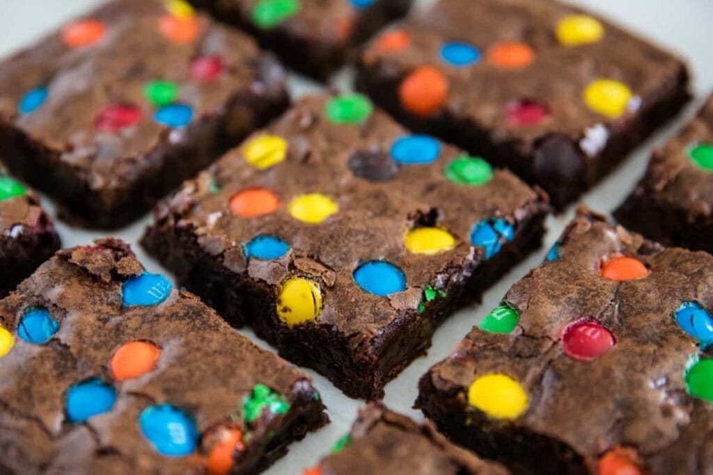 Close-up of M&M brownies cut into squares with colorful chocolate candies on top.