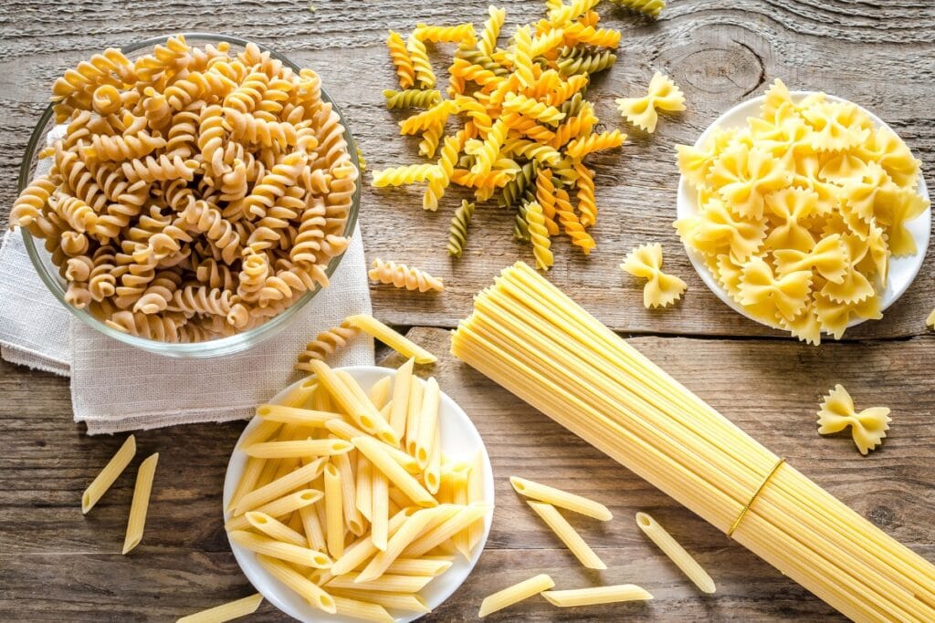 Different kinds of pasta on wooden table.