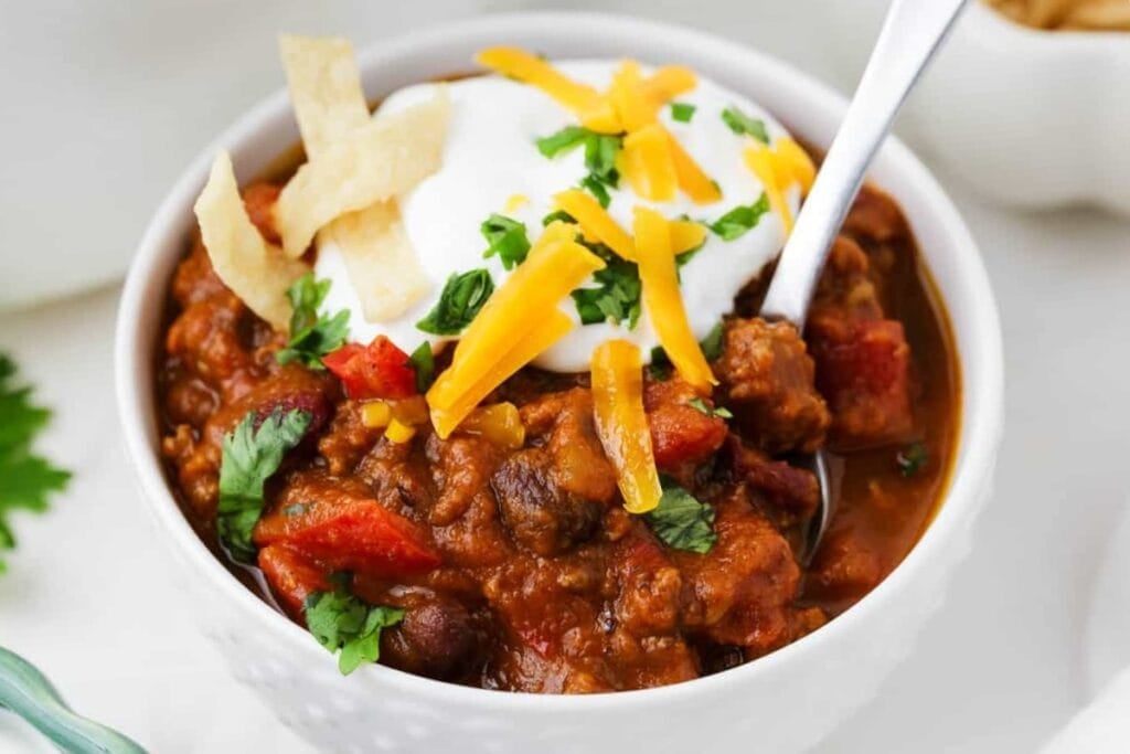 Pumpkin Chili topped with sour cream, cheese, and parsley in a bowl.