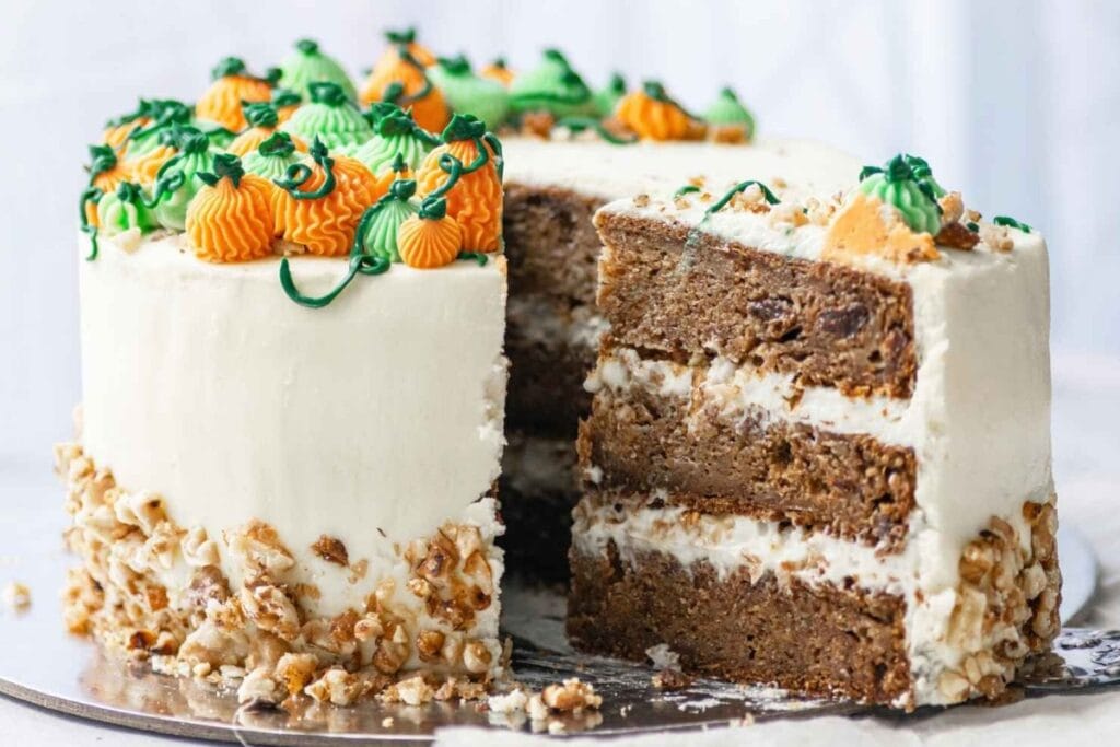 Pumpkin layer cake with frosting and pumpkin decorations, with a slice cut out.