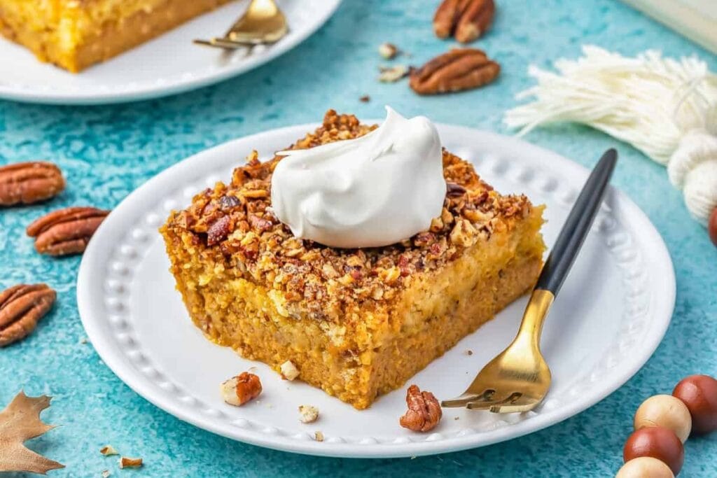 Pumpkin crunch cake topped with whipped cream on a plate.