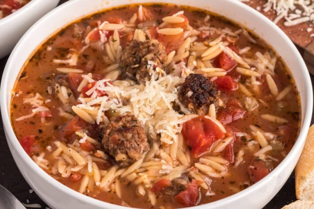 Sausage tomato orzo soup in a bowl.