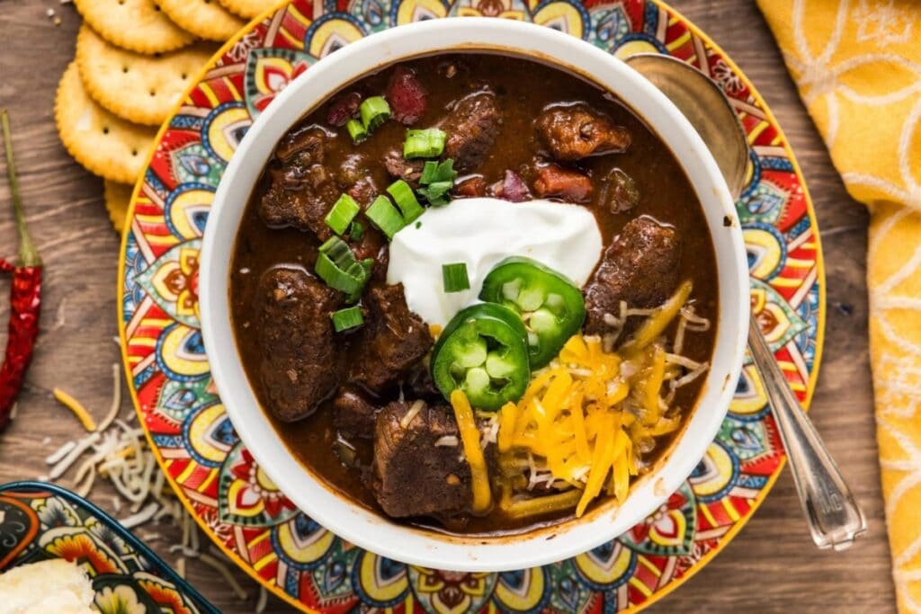 Top view of Short Rib Chili in a bowl with a spoon on the side.