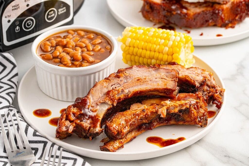 Slow cooker baby back ribs coated in barbecue sauce on a plate.