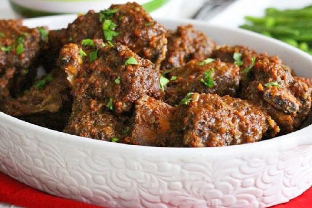 Slow cooker beef short ribs in a white serving dish, topped with chopped parsley.