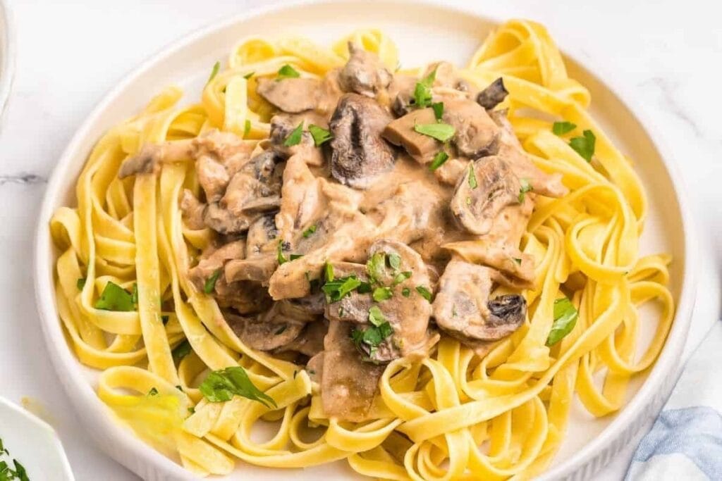 Slow cooker chicken stroganoff served with pasta on a plate.