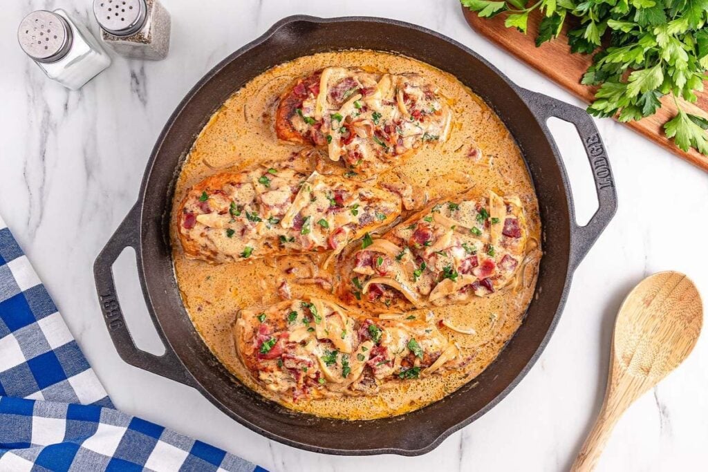 Smothered chicken in a skillet with creamy gravy.