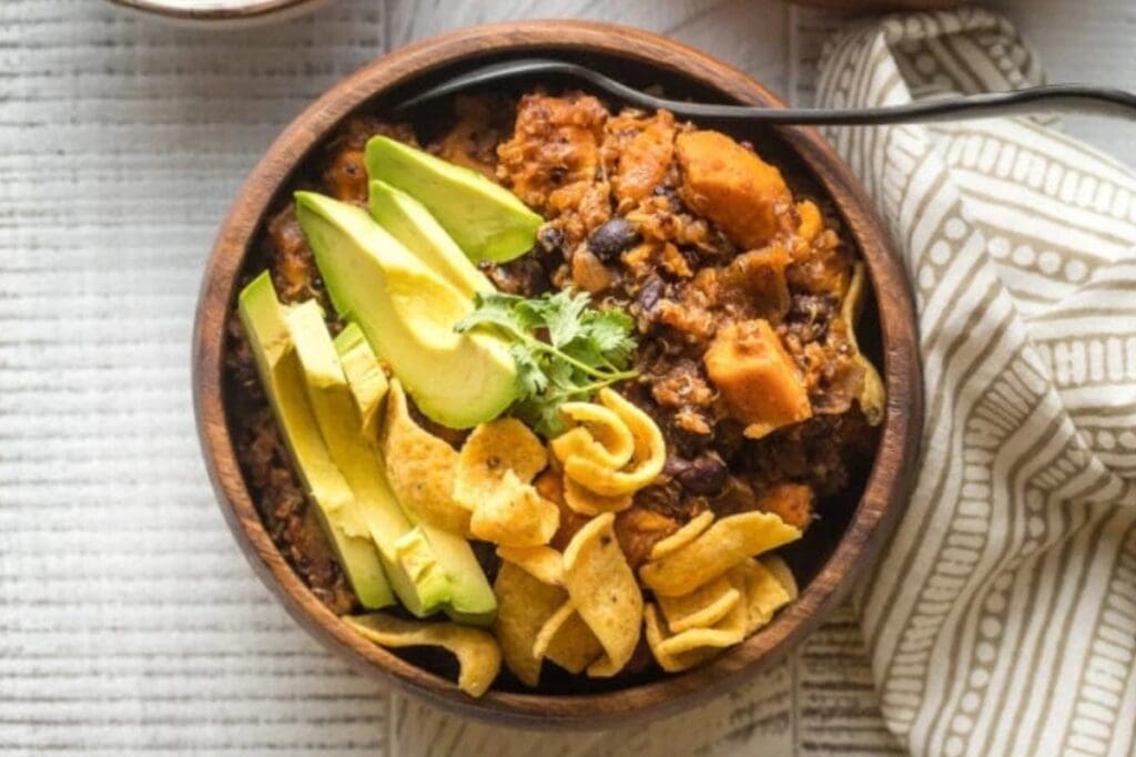 Top view of Sweet Potato Black Bean Chili in a bowl with avocado slices and Fritos.