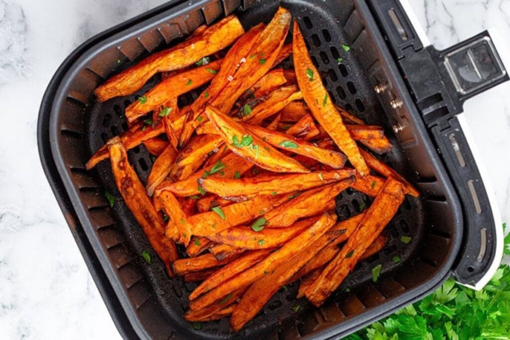 Sweet potato fries in an air fryer basket.