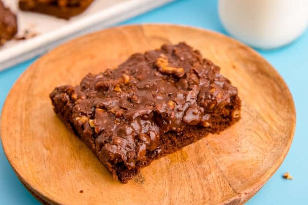 Slice of Texas sheet cake on a round wooden board.