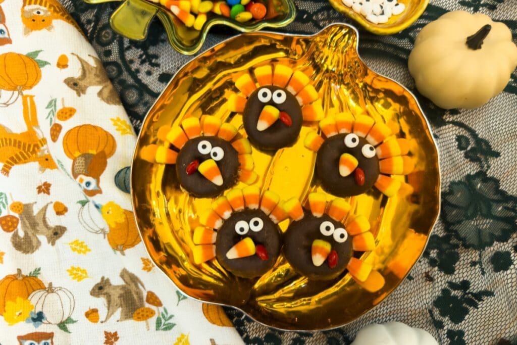 Close-up of five turkey donuts with candy corn feathers on a pumpkin plate.