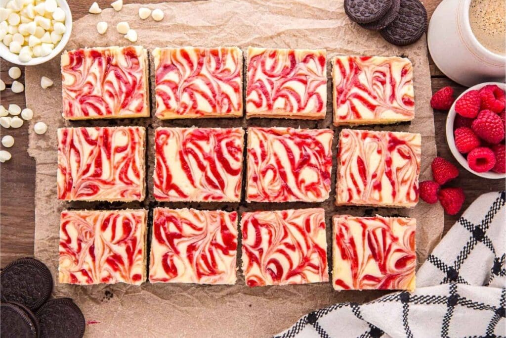 White chocolate raspberry cheesecake bars on a wooden table.