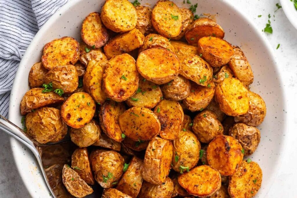Air-fried baby potatoes with herbs in a white bowl.