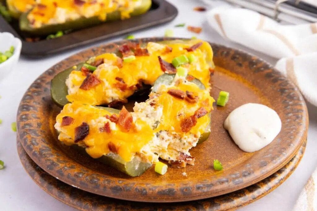 Stuffed pickles with chicken, bacon, and cheese on a brown plate with ranch.