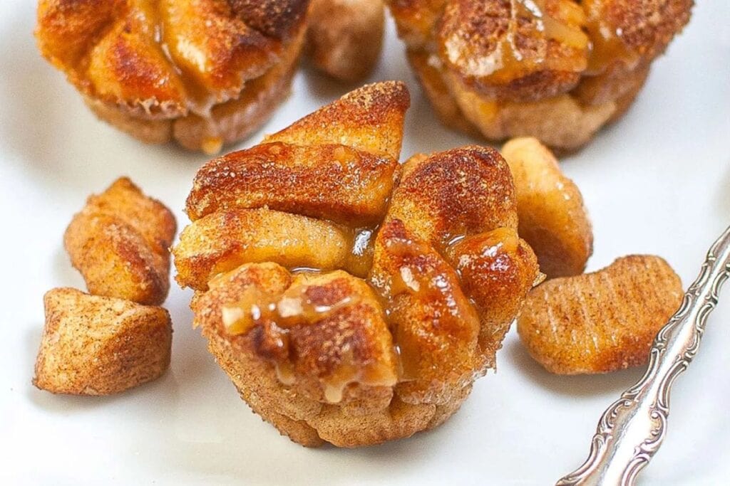 Close-up of a glazed monkey bread muffin on a white plate.