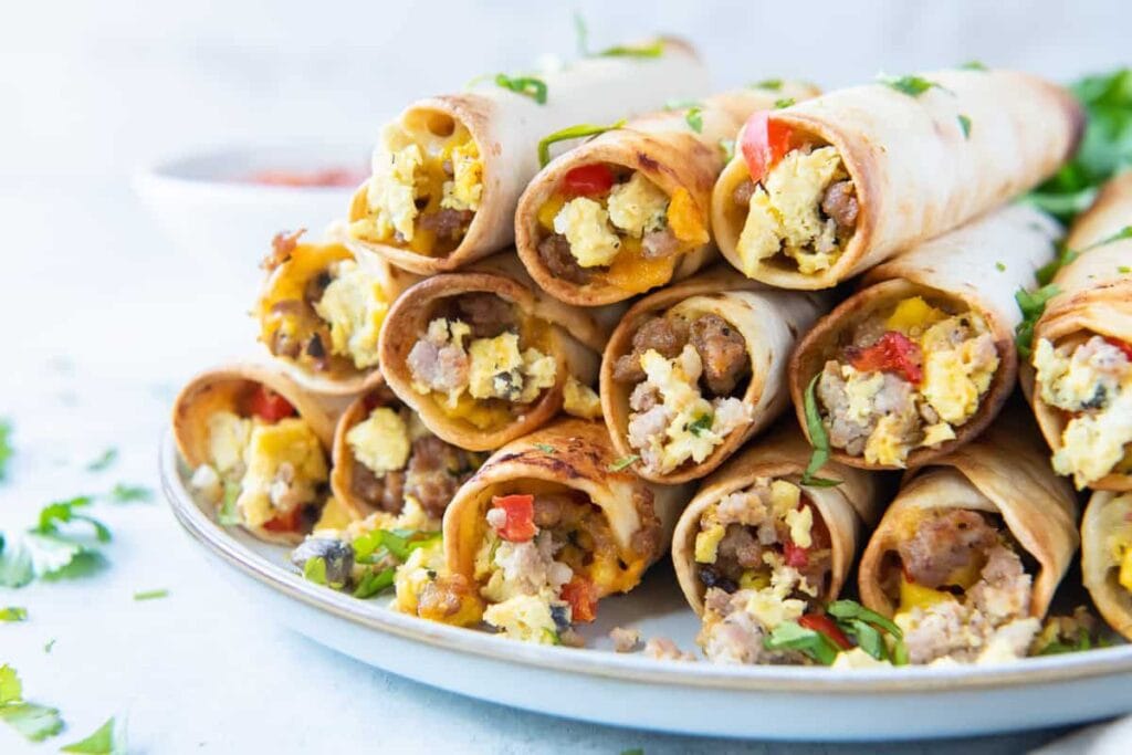 A stack of breakfast taquitos filled with eggs, sausage, and cheese on a plate.