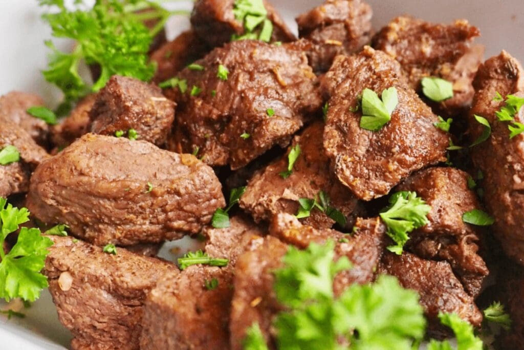 Close-up of cooked beef tips garnished with fresh parsley.