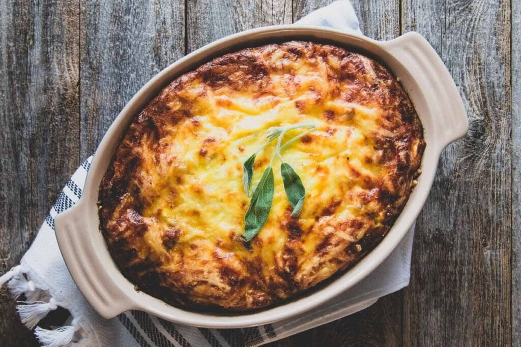Cheesy potato casserole with sausage and eggs in a baking dish.