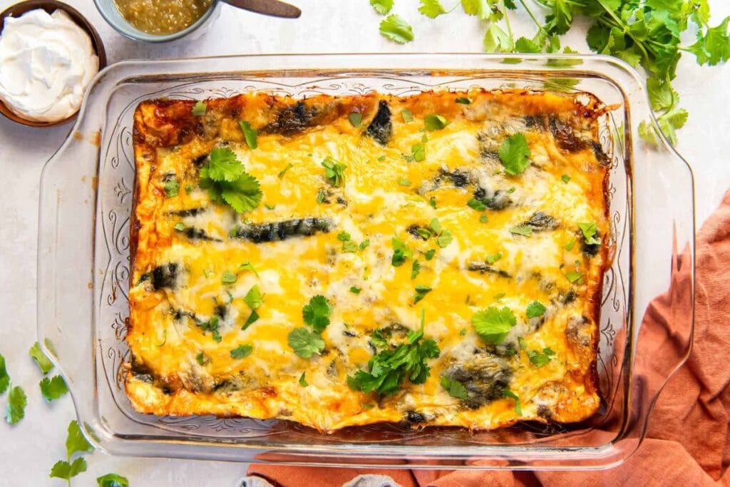 Chile relleno casserole with melted cheese and cilantro in a glass dish.