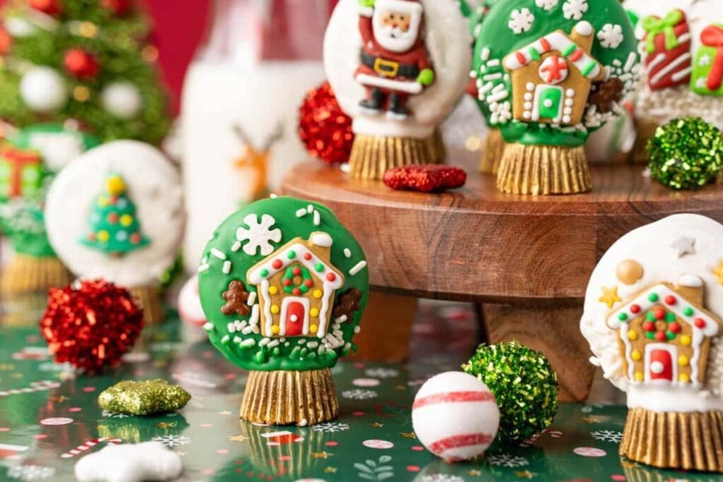 Christmas Oreo snow globe cookies decorated with gingerbread houses and Santa.