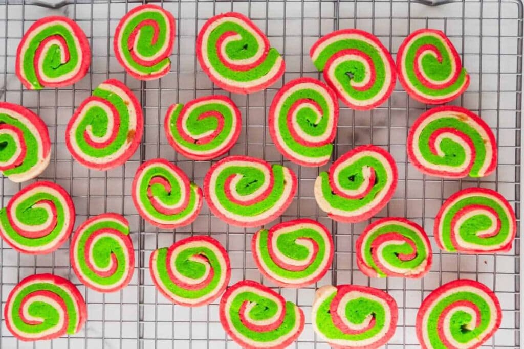 Overhead shot of red, green, and white pinwheel cookies on a cooling rack.