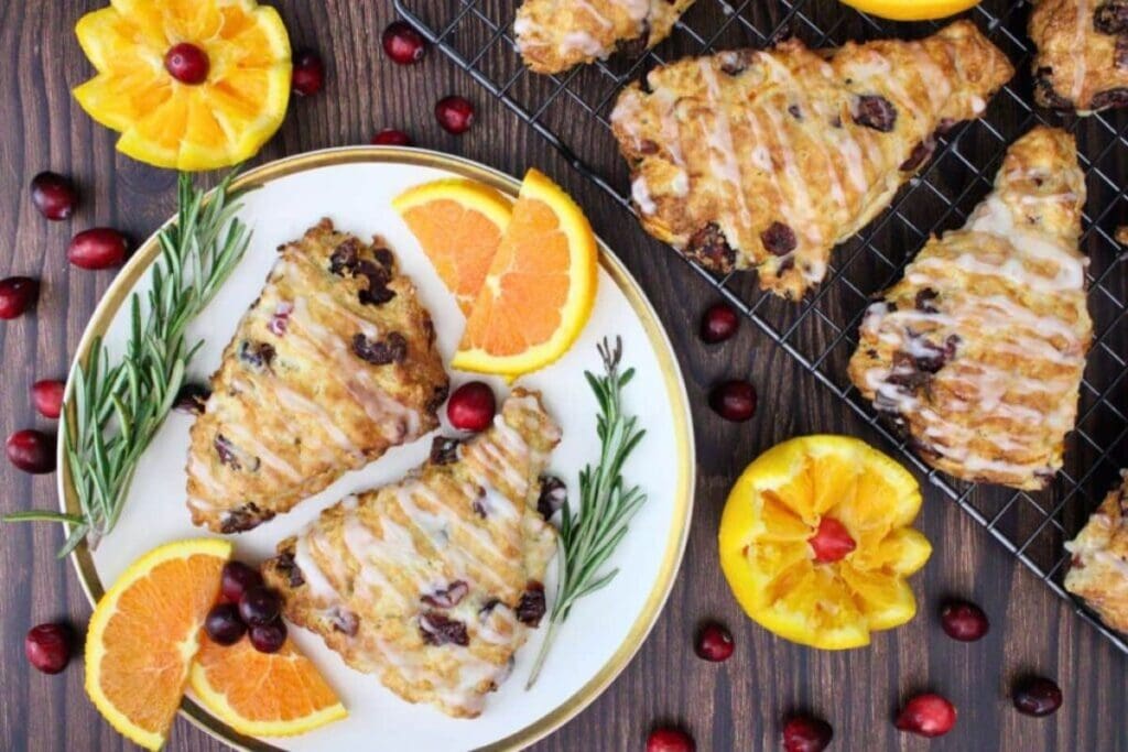 Overhead shot of glazed cranberry scones with orange slices and cranberries.