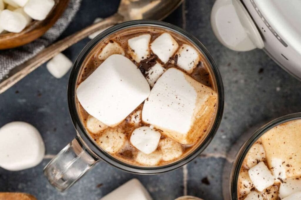 Overhead view of hot chocolate with marshmallows in a glass mug.