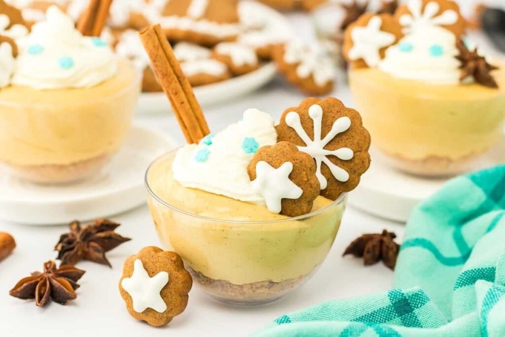 Dessert cups with gingerbread cookies, whipped cream, and a cinnamon stick.