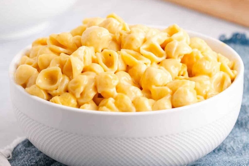 Mac and cheese in a white bowl on a blue cloth.