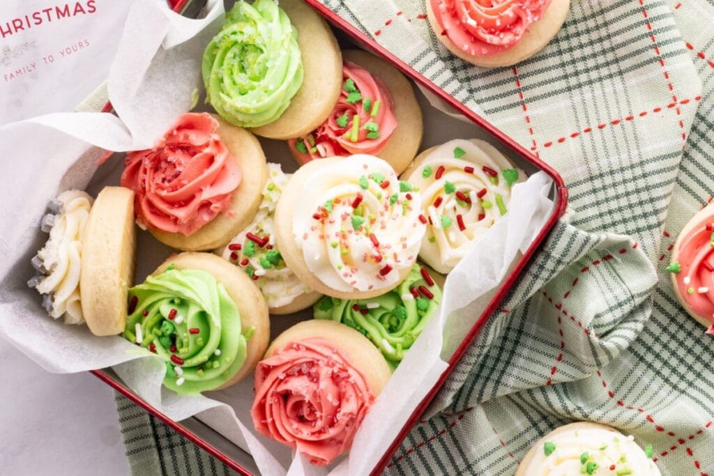 Frosted Lofthouse cookies in a red tin with green plaid fabric.