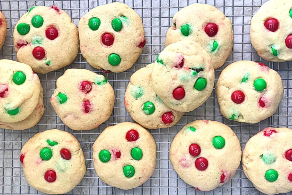 Overhead shot of M&M cookies with red and green candies on a wire rack.