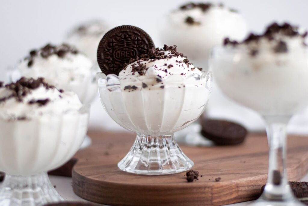 Oreo mousse in dessert cups, topped with crushed Oreos and a whole Oreo.
