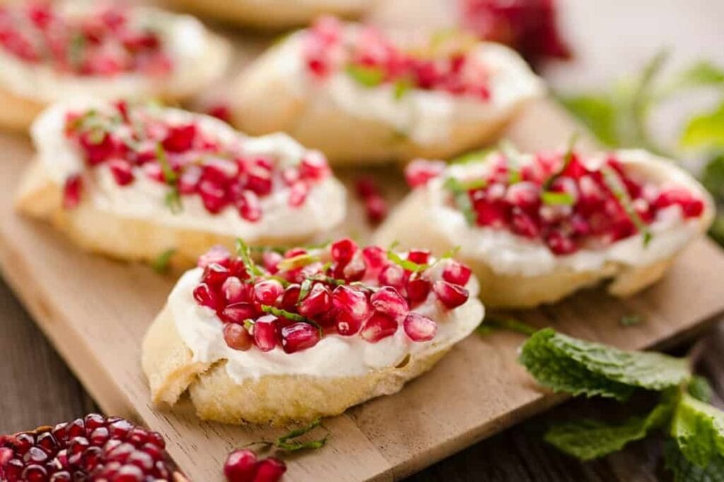 A close up shot of crostini with pomegranate.