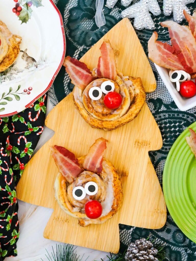 A close up shot of Reindeer cinnamon rolls on a wooden board.