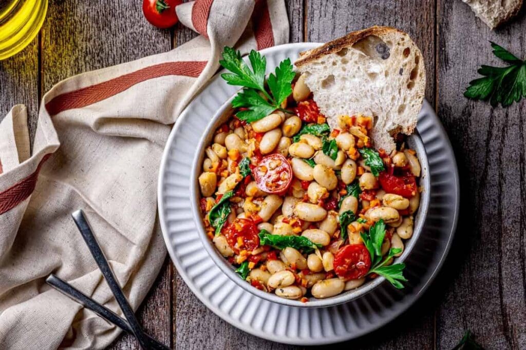 Sautéed Italian white beans with tomatoes and spinach in a bowl with bread.
